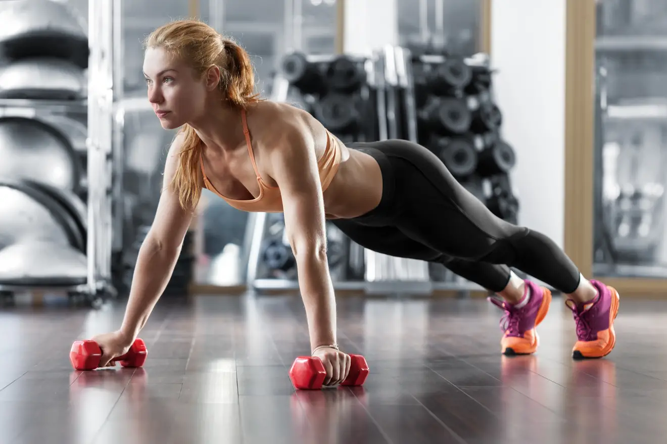 Woman doing push-ups with dumbbells in hands