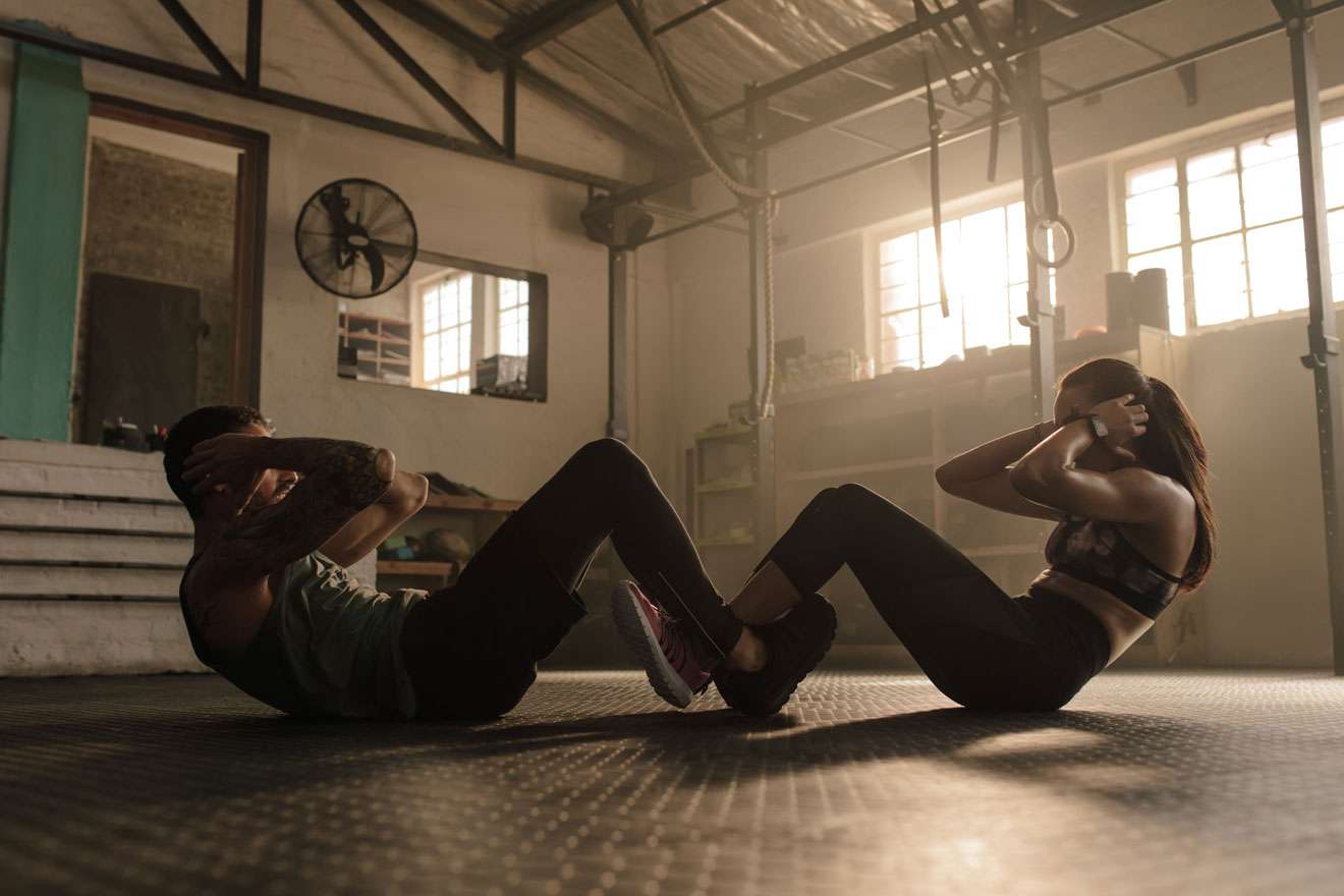 Man and woman locking legs and doing situps