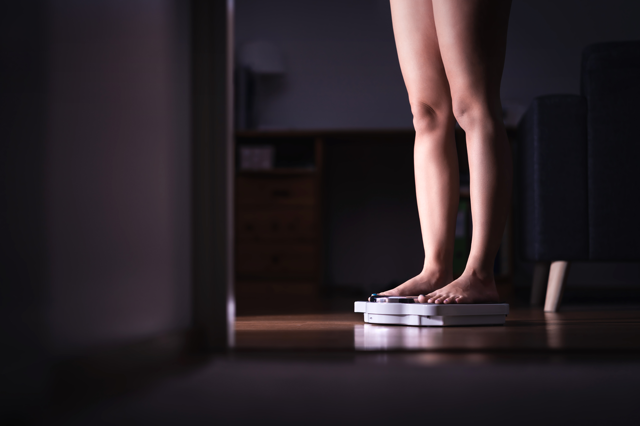 Woman standing on scale in bathroom