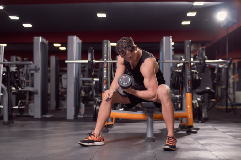 Man sitting on bench doing dumbbell concentration curl
