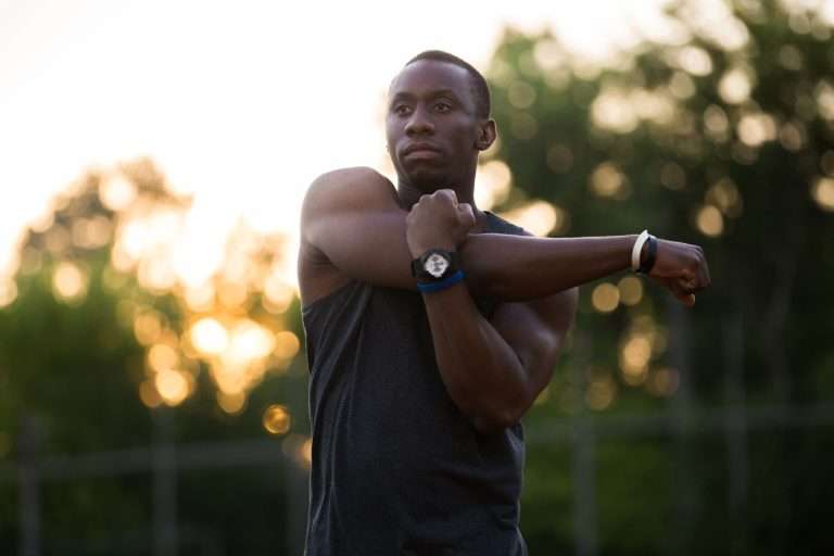 black man stretching his shoulders outside