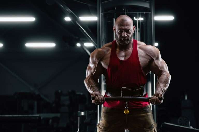 Muscular man in gym doing cable biceps curl