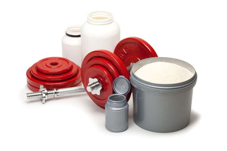 Whey proteins and dumbbells on white floor
