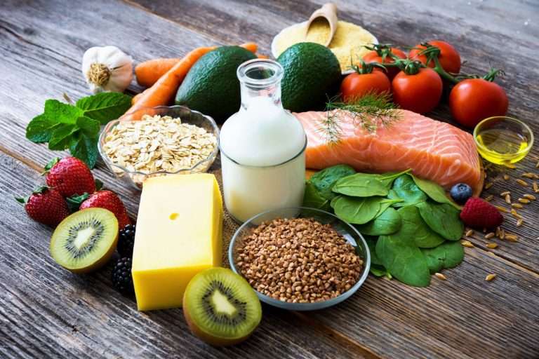 Milk, cheese, salmon, fruits and vegetables on a wooden table